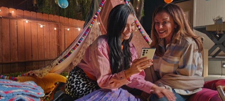 Une mère et sa fille dans leur cour la nuit en train de regarder un Galaxy S22 Ultra.