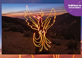 A man at sunrise makes a light painting of a rising phoenix in the air. Master it. Creator classes.