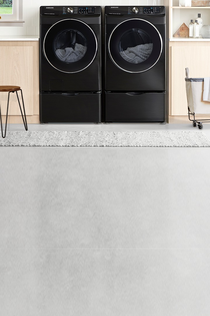 Une salle de lessive moderne avec la nouvelle laveuse intelligente à chargement frontal de 5,2 pi³ avec technologie Super Speed et sécheuse assortie en acier inoxydable noir montrée à l’avant.
