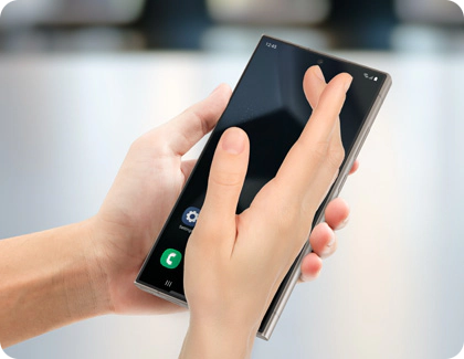 Une main effectuant un geste de glissement de la paume sur un téléphone Samsung Galaxy pour effectuer une capture d’écran.
