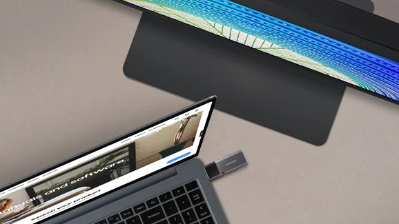 Ordinateur portable avec une clé USB connectée à côté d’un téléviseur Samsung.
