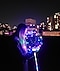Sommernachtsfoto einer Frau, die einen leuchtenden LED-Ballon hält, während im Hintergrund Bokeh-Lichter zu sehen sind