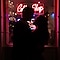 Schattenfoto eines Pärchens vor der Neonbeleuchtung eines Cafés. Die Kulisse ist dunkel, aber ihre Silhouette ist erkennbar