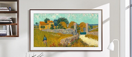 Un téléviseur Samsung The Frame 2020 accroché au mur affiche une œuvre d’art au milieu d’autres tableaux et cadres photo.