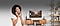 Une femme sourit et parle au téléphone. Derrière elle, est visible un salon propre avec une télévision Samsung sur le mur avec le son coupé.