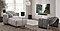 En una acogedora sala de estar, hay una TV montada en la pared y un par de barras de sonido, así como dos altavoces traseros en un soporte colocado justo detrás de un sofá.