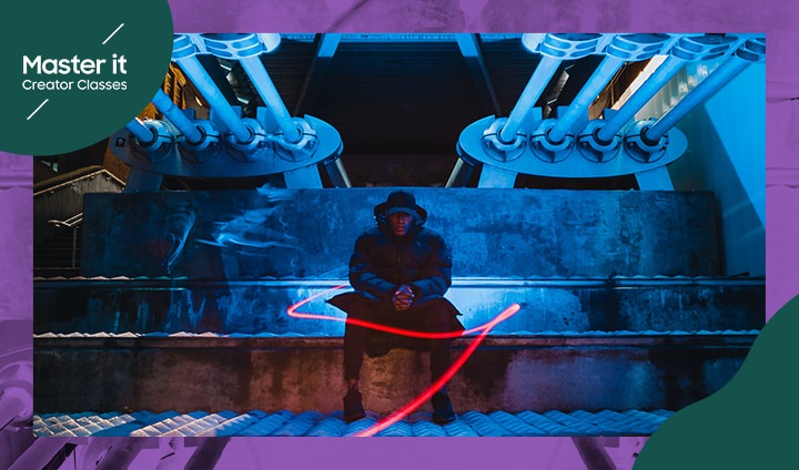 Un hombre vestido de negro sentado en unos escalones en una calle oscura de la ciudad, con una estela de luz roja delante de él. “Master it. Creator Classes”.
