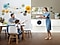 Una madre, un padre y un hijo pequeño están todos vestidos con prendas delicadas. La madre lleva un pastel de fresa a la mesa, donde el hijo y el padre están sentados uno frente al otro. La lavadora QuickDrive™ está perfectamente ubicada en la mesada que se muestra atrás.