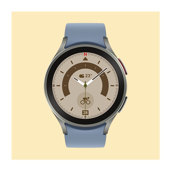 Eine schwarze Galaxy Watch5 Pro mit einem khakifarbenen geriffelten Sportband und einem analogen Premium-Zifferblatt wird auf auf einer beigefarbenen Kachel gezeigt.