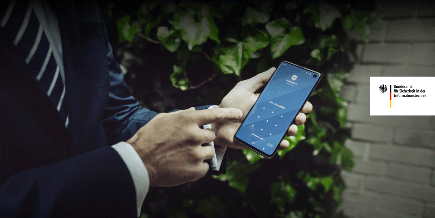 Mitarbeitender in Anzug deutet auf Samsung Device in seiner Hand, Knox-Sicherheitsscreen auf dem Device, BSI IT Sicherheit.