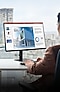 Ein Büroangestellter bearbeitet eine PowerPoint-Folie auf einem QHD-Monitor.
