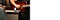 Im Hintergund ist eine Hand auf einer Gitarre zu sehen. Im Vordergrund liegt das Galaxy Z Flip6 halb zusammengefaltet auf einer Musikbox.