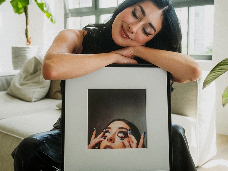 Elif hält stützt sich verträumt auf den Samsung Music Frame.