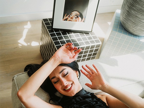 Elif liegt auf einer Couch, in der Nähe steht der Samsung Music Frame.