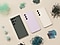 Le Galaxy s23 Ultra couleur Phantom Black et le Galaxy S23 couleur Lavender et Cream sont placés côte à côte sur une surface beige. Tout autour, différents matériaux recyclés tels que les filets de pêche, les pièces de bouteilles en PET et de fûts d’eau ainsi que les petits plastiques sont disposés en petits tas.
