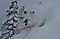Ein Skifahrer in der Luft nach einem Sprung über einen Abgrund, der von einer Wolke aus Schnee umgeben ist.
