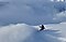 Ein Snowboarder fährt einen schneebedeckten Berg hinab. Im Hintergrund sind weitere nebelverhangene Gipfel zu sehen.