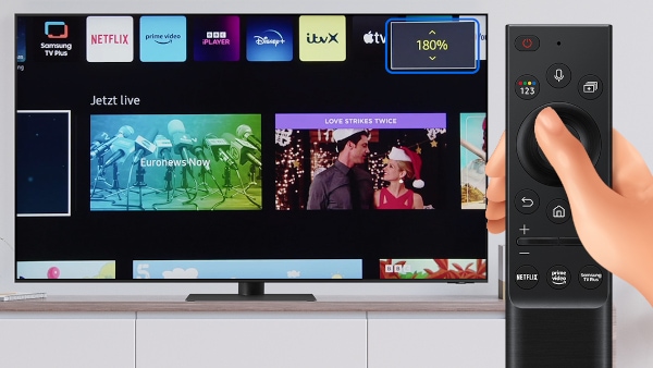 Samsung Smart TV steht auf einem Sideboard. Hand bedient Fernbedienung des Fernsehers, um den Bildschirm zu zoomen.