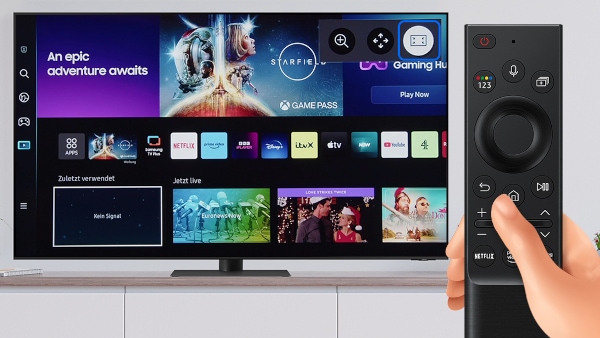 Samsung Smart TV steht auf einem Sideboard. Hand bedient Fernbedienung des Fernsehers, um den Vollbild-Modus zu verlassen.
