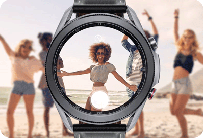 Vedere a unui Galaxy Watch care arată o previzualizare a camerei telefonului. O femeie este arătată pe plajă.