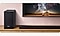 Soundbar und Lautsprecher auf einem Regal und Fernseher an der Wand