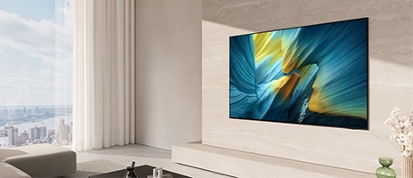 Samsung OLED TV an einer hellen Wohnzimmerwand montiert, zeigt ein farbenfrohes abstraktes Bild. Modernes, minimalistisches Raumdesign mit bodentiefem Fenster und Blick auf die Stadt.