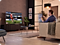 Ein Mann spielt mit einer Spielkonsole ein Fußballspiel auf einem Samsung Neo QLED TV.