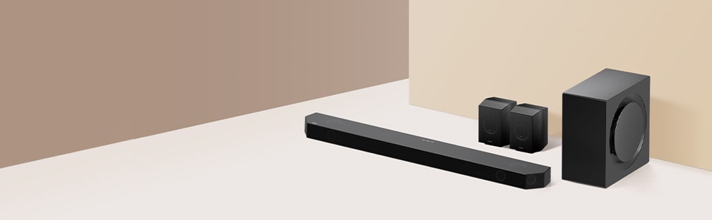 Eine Soundbar mit einem Subwoofer und zwei rückwärtigen Lautsprechern ist auf dem Boden ausgelegt.