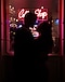 Silhuetfotografering af et par, som står foran en café med et neonskilt. Det er mørkt, men man ser deres konturer