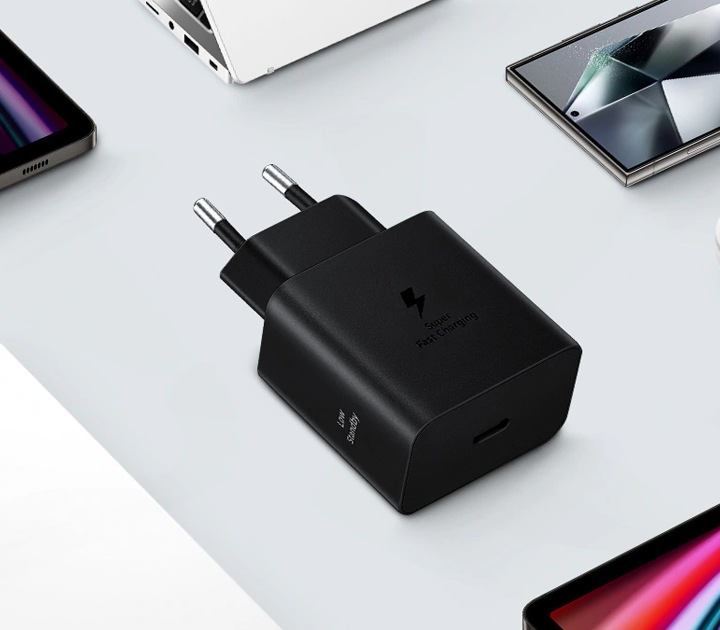 Schwarzes Ladegerät auf weißem Untergrund, umgeben von Smartphones