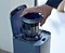 Una mano coloca el filtro de una aspiradora Samsung Jet en la Clean Station, que vacía automáticamente el polvo.