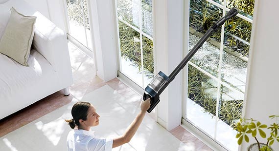 Una mujer aspira un alféizar alto con un Bespoke Jet™.