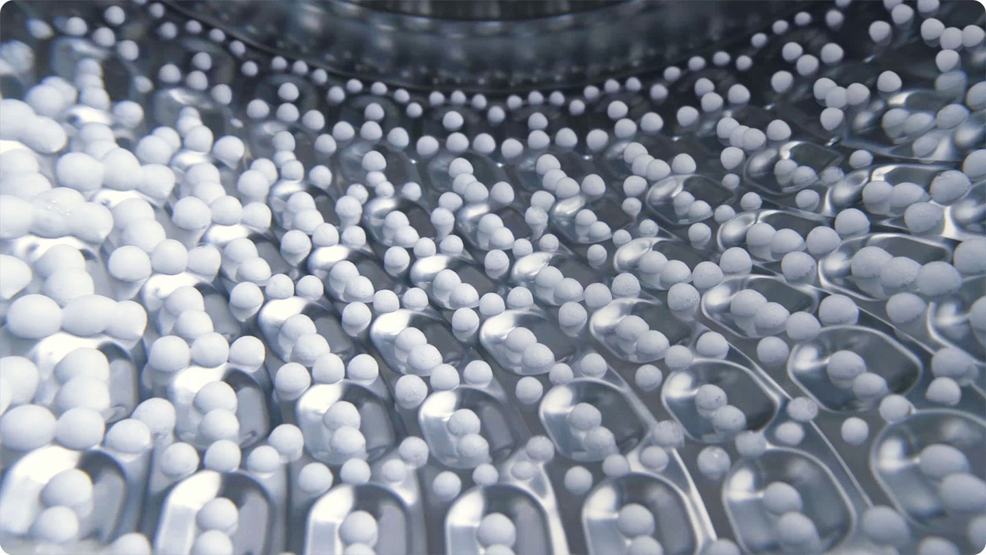 Podemos ver um close-up de bolhas de espuma a aumentar de tamanho. Aparece o texto \"Ajuste inteligente do tempo de lavagem, da temperatura e da velocidade de centrifugação. Depois a imagem passa para um tecido coberto de bolhas de espuma dentro da máquina de lavar, indicando um ciclo de lavagem. O texto \"Até 70% de poupança de energia com lavagem a frio\" aparece à direita. A imagem passa para um close-up da espuma a aumentar. E depois, passa para uma única bolha de espuma a aumentar com o texto 45,5% melhor cuidado dos tecidos.