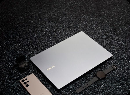 Samsung Galaxy Book4 gris fermé, accompagné du Galaxy S24 Ultra, d’une Galaxy Watch6 noire et d’écouteurs Galaxy Buds2 Pro noirs.