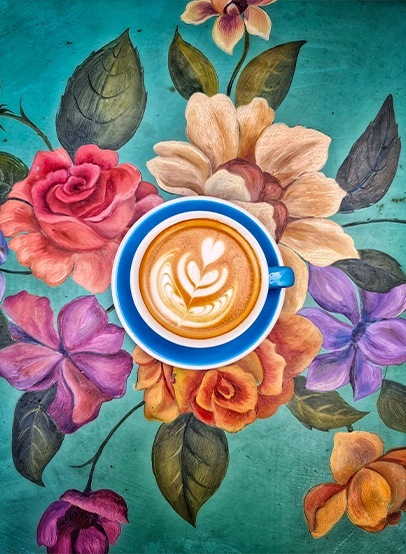 Photographie d'une tasse de café posée sur une nappe à motifs floraux