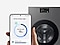 Devant un lave-linge, une main tient un smartphone Galaxy affichant le AI Mode Energy sur l'interface  SmartThings.