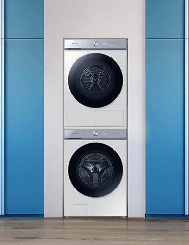 L’ensemble lave-linge et sèche-linge empilé est positionné entre une plante verte et un meuble à étagères.