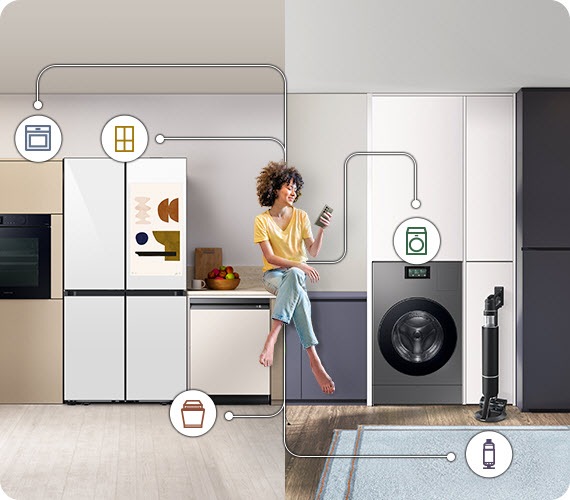 A woman is sitting on the counter of a kitchen that turns into a bathroom counter, merging the two living spaces. She is holding her phone, to which all the appliances are connected, as indicated by white lines and device icons.