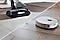 There are two types of vacuums in one frame: on the left, a Samsung Jet Stick cordless vacuum cleaner cleans the floor. On the right, a Samsung Bot robot vacuum cleaner cleans the wooden floor.