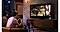 Un homme joue à un jeu vidéo dans un salon, avec un appel vidéo sur son téléphone diffusé à la télévision à côté du jeu. Le logo de PlayerUnknown's Battlegrounds (PUBG) est affiché en bas à gauche. L'ami en appel vidéo crie d'excitation tout en tenant une manette. La vue de la caméra de l'homme est affichée dans le coin inférieur de la vue de l'appel vidéo.