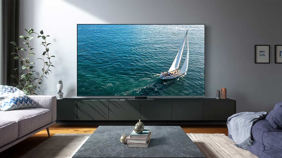 A 98 inch Supersize TV is placed in the living room area displaying a sail boat.