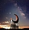 Sculpture de lune soutenue par des colonnes, avec en arrière-plan un ciel étoilé pendant le coucher du soleil