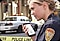 A female police officer standing at a crime scene talking into the black, rugged Samsung smartphone in her hand