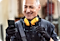 A factory worker wearing a pair of protective headphones smiles at the rugged Samsung smartphone in his hand.
