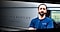 Dex for business - a man with a beard wearing a blue t-shirt leans on a silver van behind him while looking at the camera and crossing his arms.