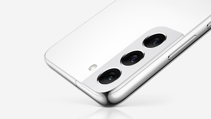 Πάνω μισό Galaxy S22+ σε Phantom White όπως φαίνεται από το πίσω μέρος του smartphone, ισορροπώντας στη μία γωνία.