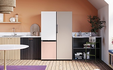 Ένας ψυγειοκαταψύκτης Bespoke με πάνω πάνελ πόρτας χρώματος Λευκού και κάτω πάνελ πόρτας χρώματος Ροδακινί βρίσκεται πλάι σε μια μονόπορτη μονάδα χρώματος Μπεζ Σατινέ σε μια μοντέρνα κουζίνα σε αποχρώσεις του ξύλου.