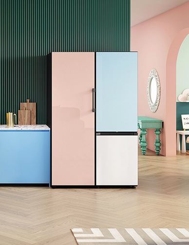 Ένα μονόπορτο Ροδακινί ψυγείο Bespoke μέσα σε μια κομψή πολύχρωμη κουζίνα πλάι σε ψυγειοκαταψύκτη με πάνελ κάτω πόρτας χρώματος Λευκού και πάνελ πάνω πόρτας χρώματος Γαλάζιου Σατινέ.