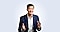 He is seated and speaking with an expressive gesture, both hands raised mid-explanation.