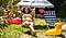 A woman with sunglasses relaxes in her backyard, surrounded by a beach umbrella, inflatable duck and lawn chair.